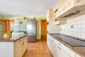 A kitchen with a refrigerator, cabinets, and a countertop with lemons.
