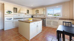 A kitchen with white cabinetry, a central island, a dishwasher, and a window with a view of the outdoors. - Villa Amland | Golf Paradise with private swimming pool (Mijas)