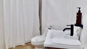 Un baño con inodoro, lavabo y cortina de ducha.