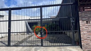 Una entrada porticada con una reja de metal, un área pavimentada y un edificio de fachada de piedra.