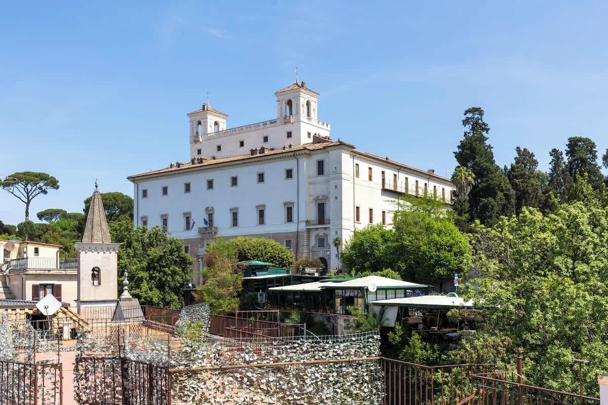 Un grande edificio bianco con un campanile e una statua di fronte.