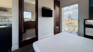 A hotel room with a bed, a TV, a bathroom with a mirror, and a view of a cityscape. - Chasing the Stars Spanish Steps Boutique Suite (Rome)
