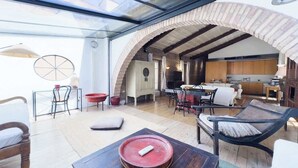 A spacious living area with a glass ceiling, a kitchen, and a dining area with modern furniture.