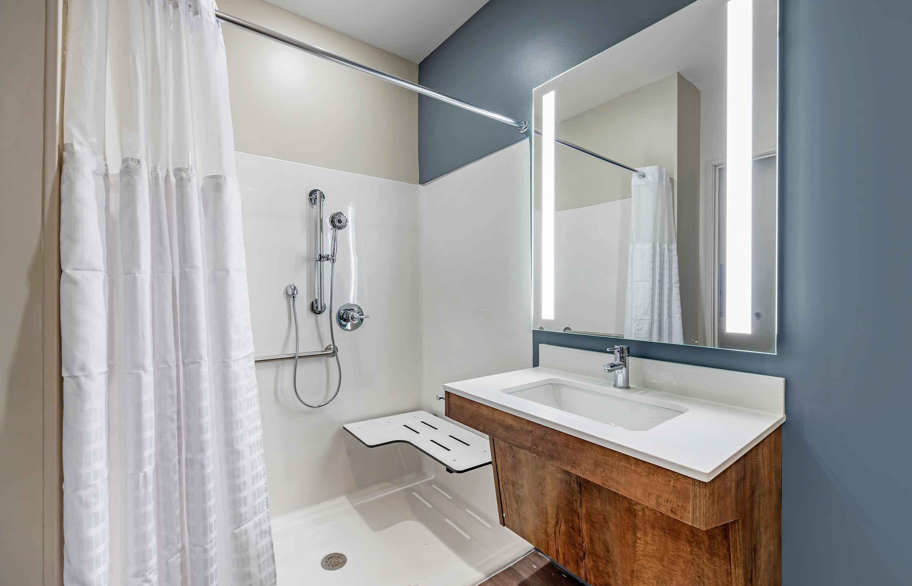 Un baño moderno con ducha, lavabo y espejo.