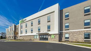 A modern hotel with a flat facade, large windows, and a prominent green logo.