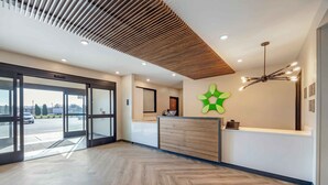 Ein Empfangsbereich mit modernem Design, mit Holzboden, einem grünen Dekorationselement und einer Rezeption.