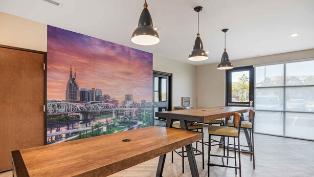 Ein moderner Konferenzraum mit einem großen Stadtbild, Holztischen und Pendelleuchten.