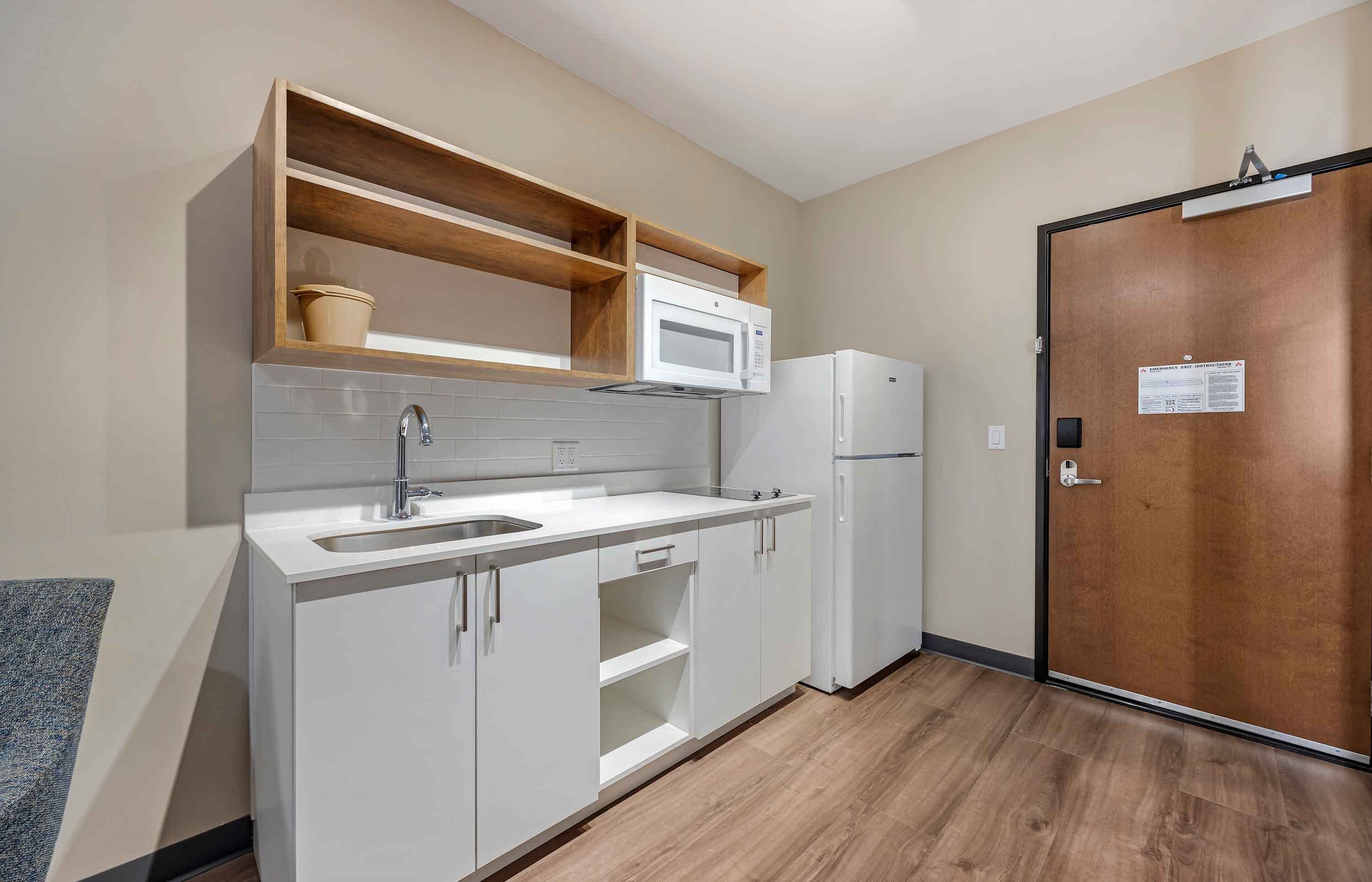 A compact kitchen with a built-in microwave, a sink, and a refrigerator.