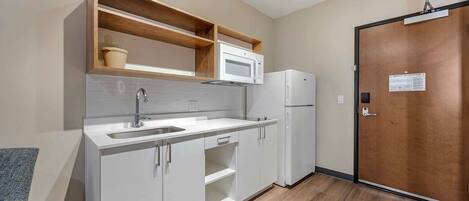 A compact kitchen with a built-in microwave, a sink, and a refrigerator.