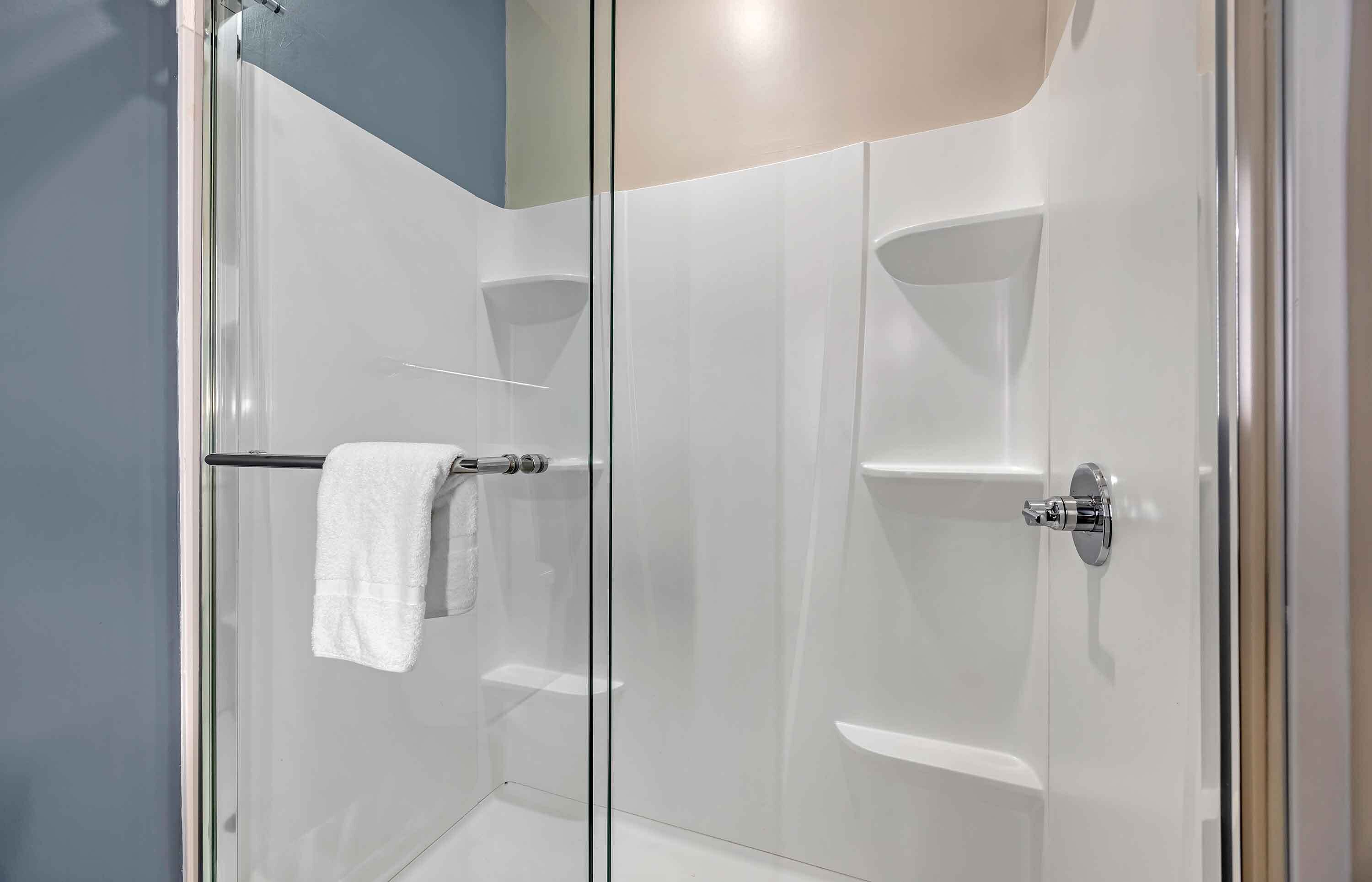 A modern shower with a glass door, a towel rack, and a chrome handle.
