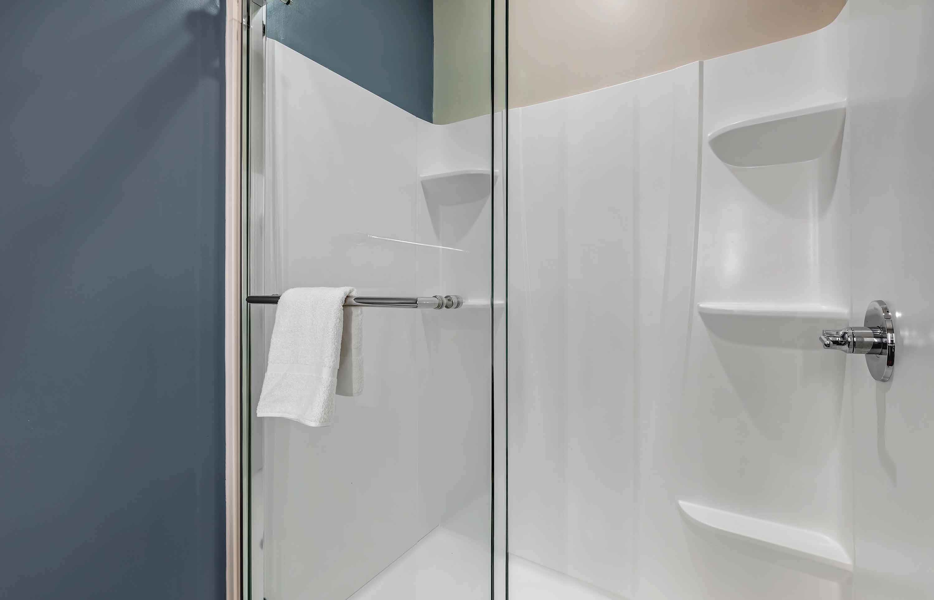 A modern bathroom with a glass shower enclosure, a towel rack, and a white sink.