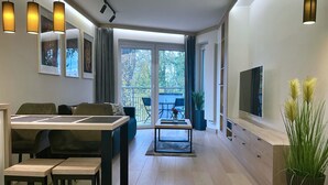 Ein modernes Wohnzimmer mit Essbereich, großen Fenstern und einem Flachbildfernseher.