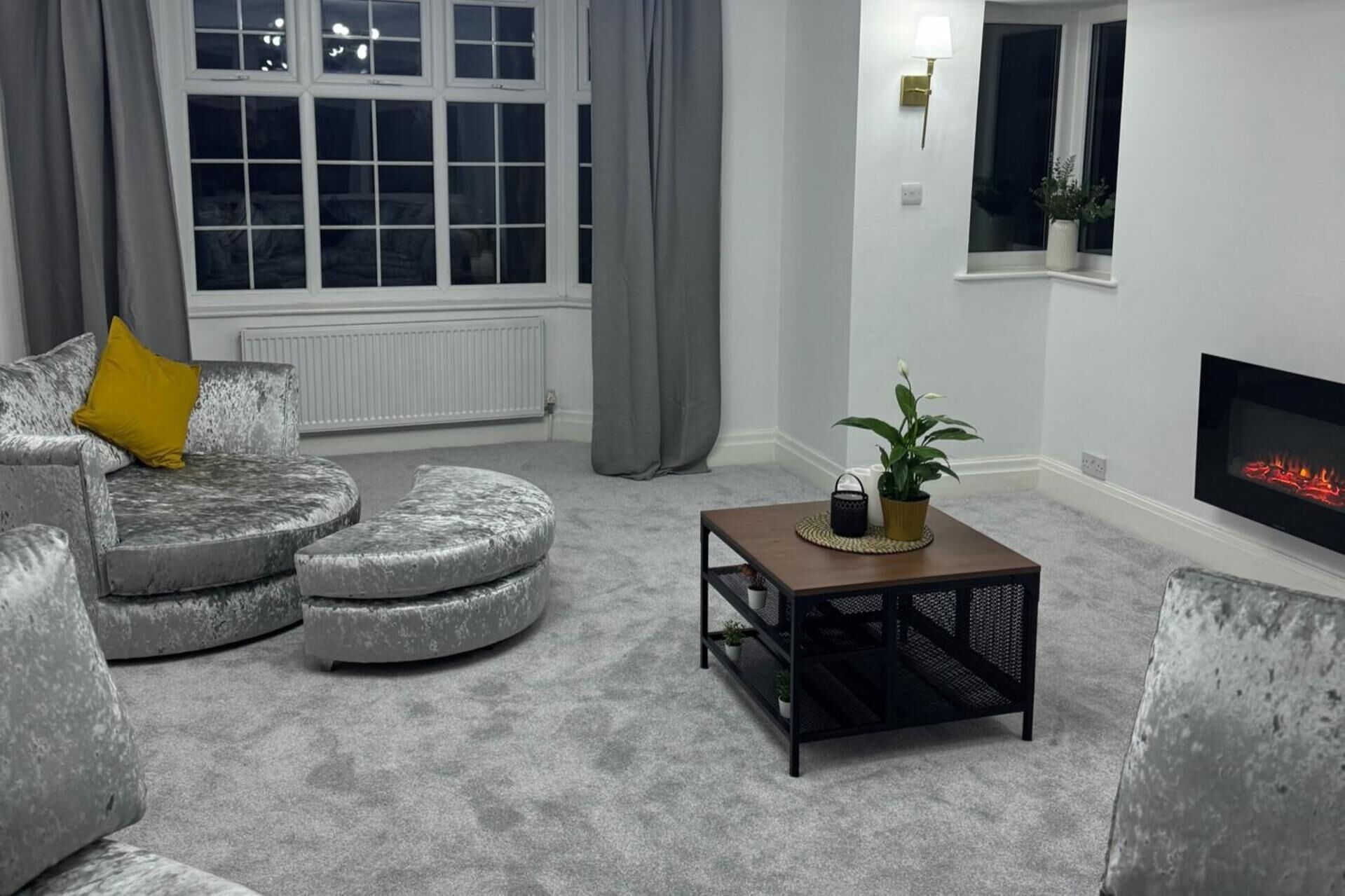 A living room with a grey sofa, a small wooden coffee table, and a fireplace.