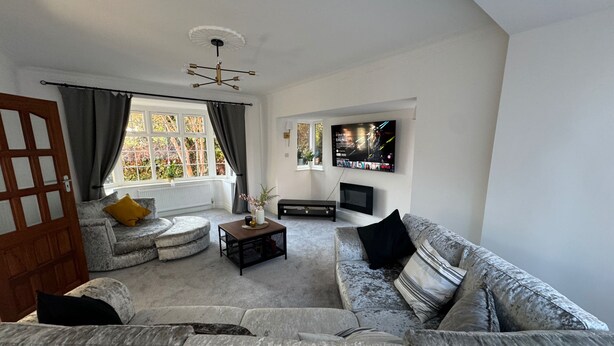 A living room with a grey sofa, a coffee table, and a TV mounted on the wall.