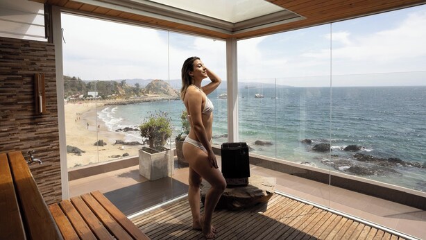 Een moderne kamer met een groot raam met uitzicht op een strand.