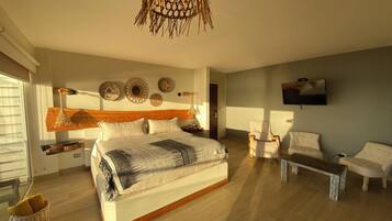 A bedroom with a large bed, a TV mounted on the wall, and a wooden floor.
