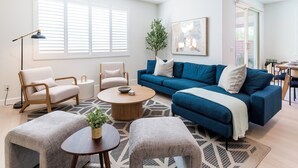 A modern living room with a blue sofa, two armchairs, a coffee table, and a floor lamp.