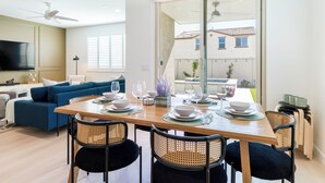 A modern dining area with a wooden table set for four, surrounded by black chairs with woven backs.