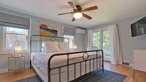 Une chambre à coucher avec un lit, un ventilateur de plafond, une fenêtre et une vue sur l’extérieur.