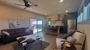 Una sala de estar moderna con un sofá, una mesa de centro y un comedor con una cocina al fondo.