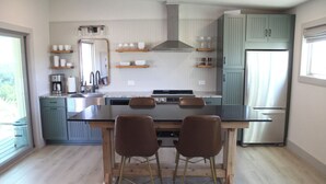 Una cocina moderna con una isla central, dos taburetes de bar y un horno empotrado.