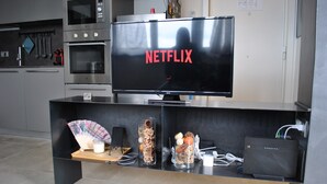 A modern kitchen with a built-in oven, microwave, and a flat-screen TV displaying 'NETFLIX' on the screen.