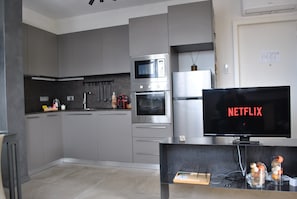 A modern kitchen with built-in appliances, a flat-screen TV displaying 'NETFLIX,' and a small wooden side table. - Prestigious Apartment near the centre of Rome - NEW (Roma)