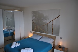 A bedroom with a bed, bedside tables, a hanging light fixture, and a wall-mounted artwork. - Prestigious Apartment near the centre of Rome - NEW (Roma)