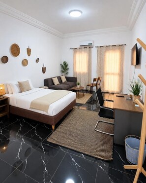Una habitación de hotel con una cama, un escritorio, una silla, un televisor y una planta.
