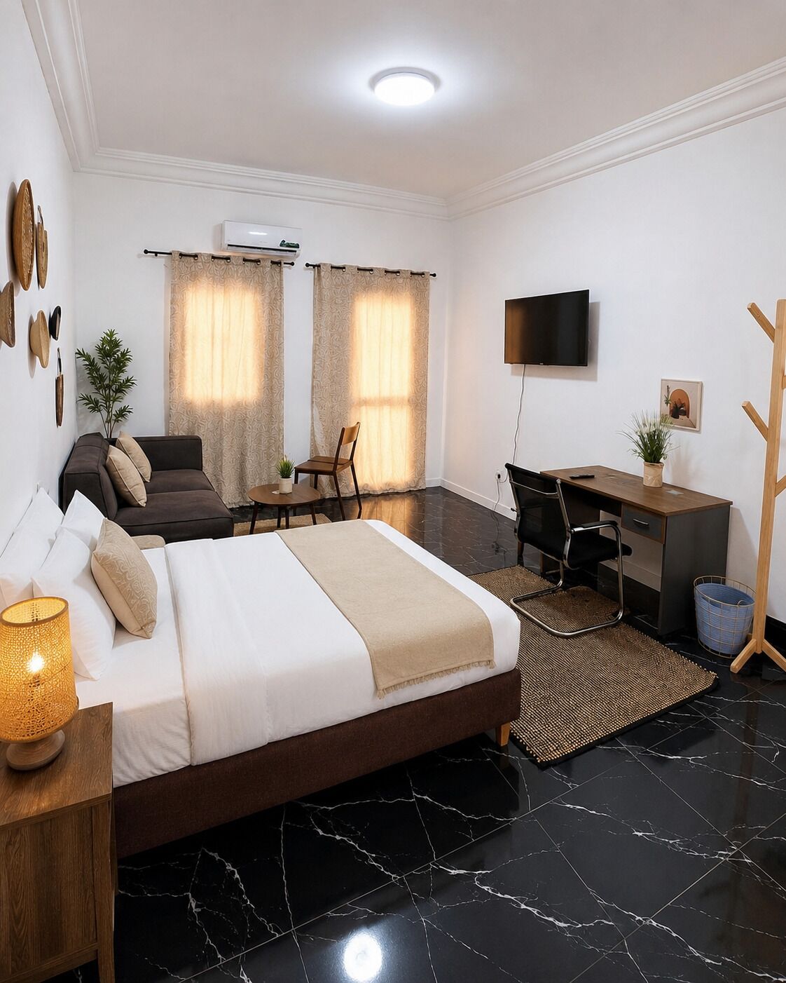 Ein modernes Hotelzimmer mit Bett, Schreibtisch, Stuhl, Fernseher und einer Pflanze.