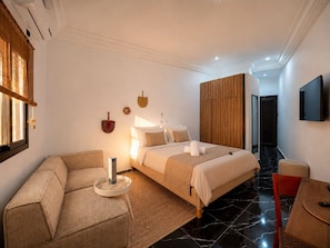 A hotel room with a bed, a sofa, a TV, and a wardrobe.