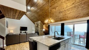 Una cocina moderna con una isla grande, detalles de piedra y vistas a un balcón.