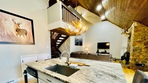 Una cocina moderna con encimera de mármol, lavaplatos integrado y una mesa de comedor de madera.