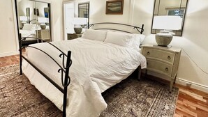 A bedroom with a bed, bedside tables, a mirror, and a rug.