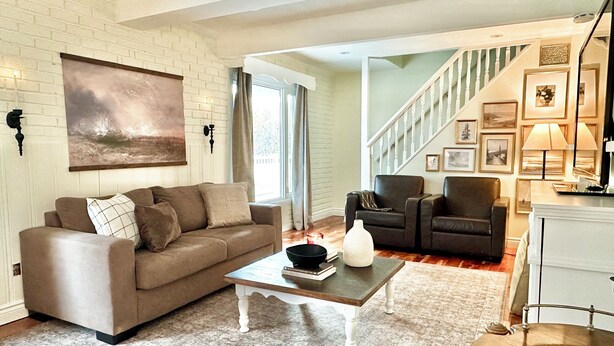A living room with a brown sofa, a coffee table, and a staircase leading to another level.