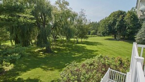 A well-maintained lawn with trees and a white fence.