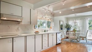 A modern kitchen with white cabinetry, a large island, and a dining area with a table and chairs.