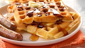 Un piatto di waffle con sciroppo e salsiccia.