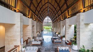 A spacious lobby with a high ceiling, stone walls, and a central seating area with sofas and tables.
