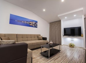 Relax in this stylish living room with a curved sofa, flat-screen TV, and glass coffee table.