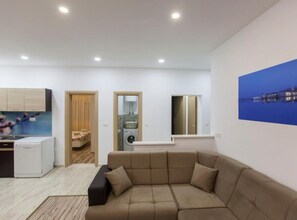 Relax in this spacious living room with a comfortable sofa and ottoman, surrounded by a neutral color palette and a view of the outside.