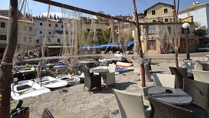 Un port de plaisance avec des bateaux amarrés, des tables et chaises installées à l’extérieur, et des bâtiments en arrière-plan.