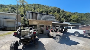 Dos vehicles tout terreny estacionats davant d'un edifici amb teulada metàl·lica i garatge.