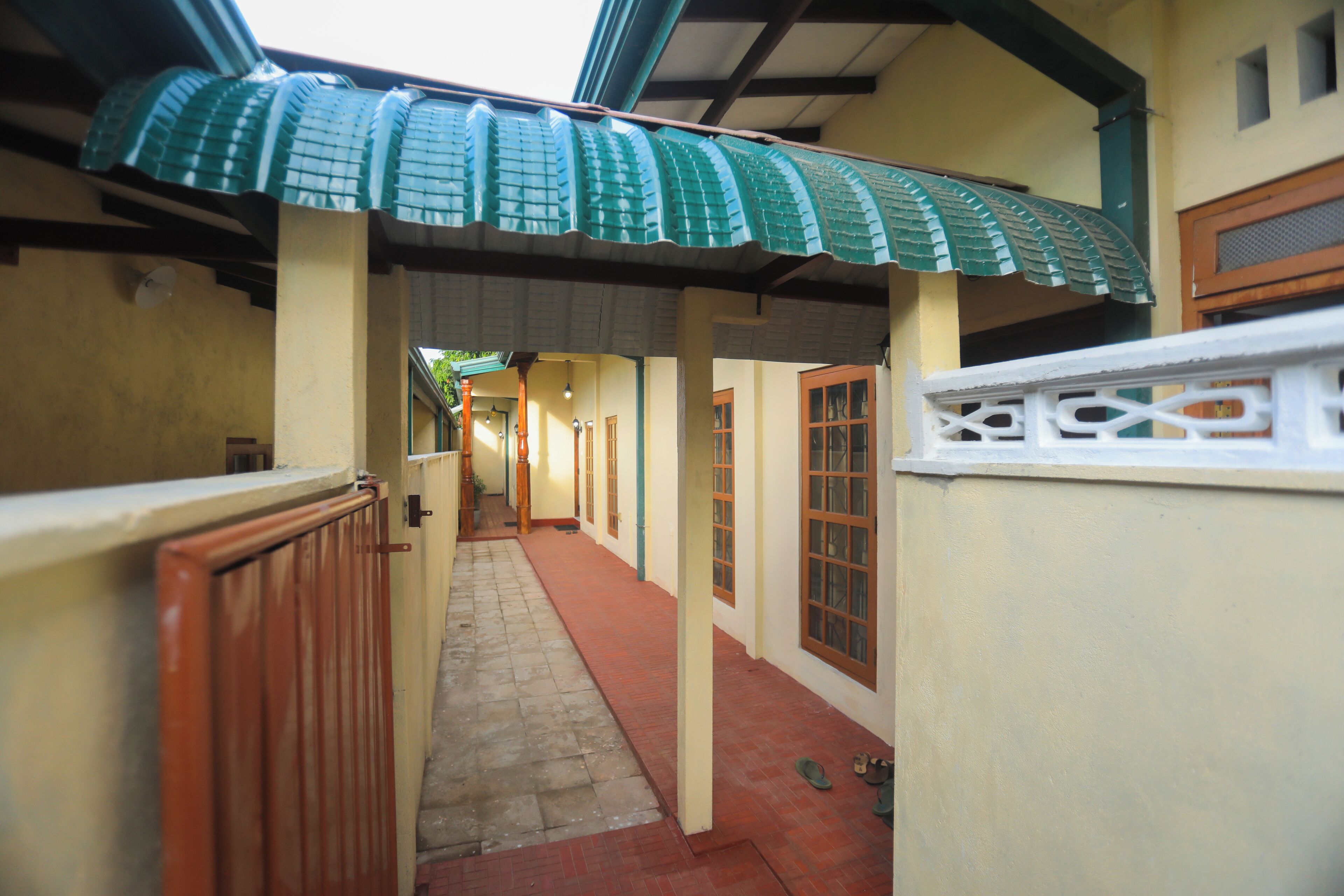 A narrow corridor with a tiled floor, a green awning, and a wooden door.
