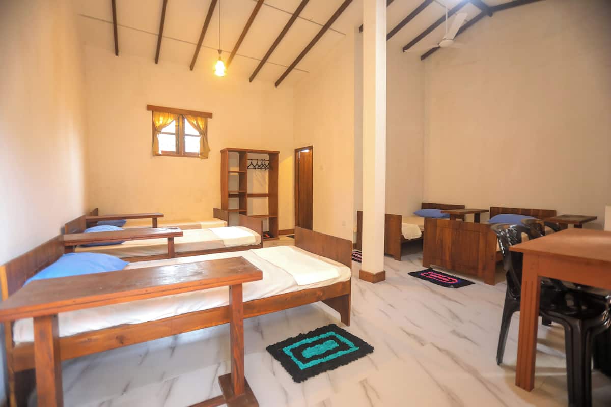 A room with two wooden beds, a wooden table, and a chair.
