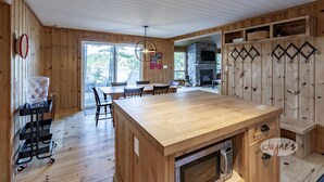 A wooden interior with a central island, a stone fireplace, and a view through large windows. - Darling 3 bed 2 bath cottage on Lake Joseph with Bunkie! NW Exposure! Boathouse (Seguin)