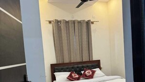 Une chambre à coucher avec un lit, un ventilateur de plafond et une fenêtre avec des rideaux.