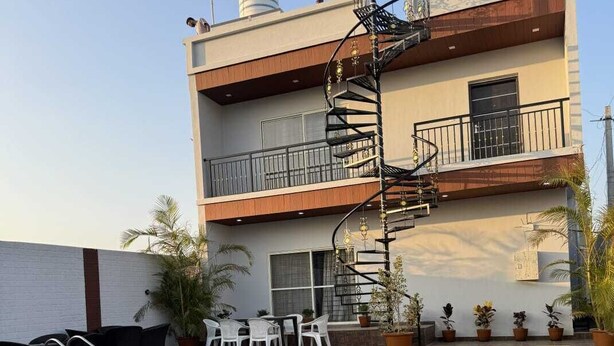 Une piscine dotée d’un espace extérieur aménagé dans un style moderne, un bâtiment à deux étages avec un escalier en colimaçon et un réservoir d’eau situé sur le toit.