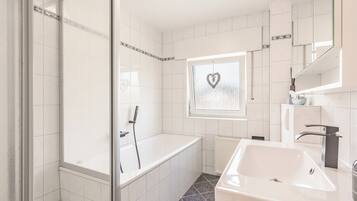Un bagno moderno con vasca, doccia e lavabo.