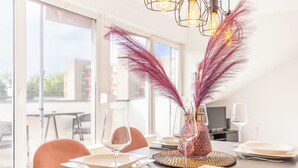 A dining table set with plates, glasses, and a decorative vase with feathers.